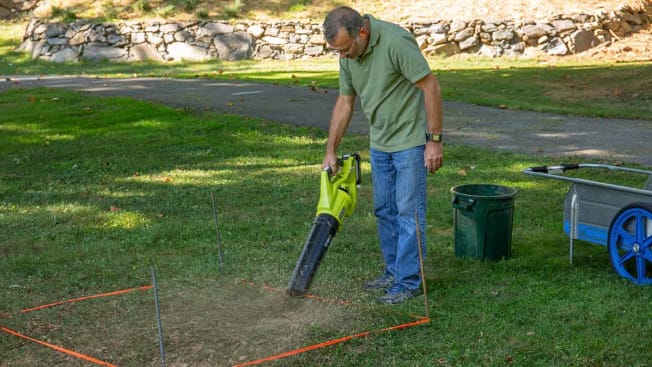 person testing leaf blower on lawn within orange marked off area